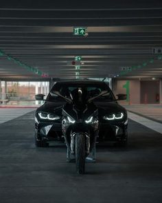 two motorcycles parked next to each other in a parking garage with green lights on the ceiling