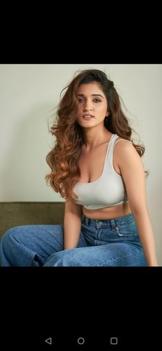 a woman sitting on top of a bed wearing jeans