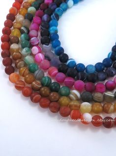 multicolored glass beads are arranged together on a white surface, with one bead in the middle