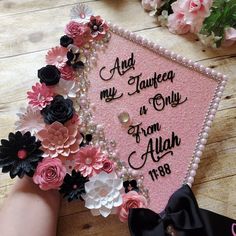 a pink graduation cap decorated with flowers and writing on the front is being held by someone's hand