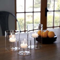 three clear glass candle holders on a table