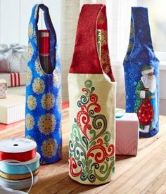 three wine bottles are sitting on a table next to some spools of thread