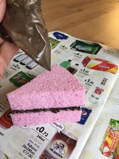 a piece of pink cake sitting on top of a table next to a bag of soda