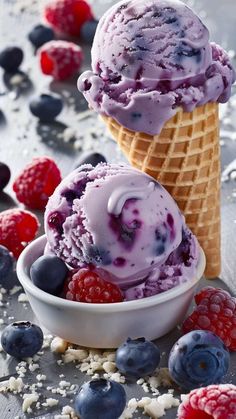 two scoops of ice cream with blueberries and raspberries on the side