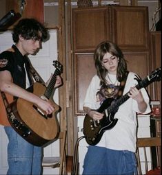 two young people are playing guitars in the kitchen