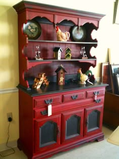 a red china cabinet with clocks on top