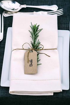 a place setting with napkins, silverware and an empty tag tied to it