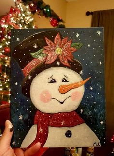 a hand holding up a card with a snowman wearing a hat and scarf on it