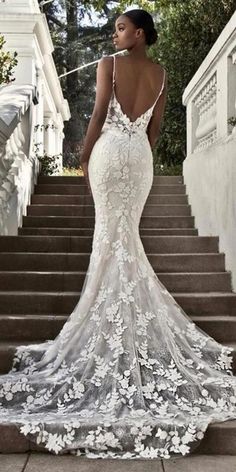 a woman standing on some steps wearing a dress with floral appliques and an open back