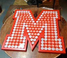 the letter m is made out of buttons and magnets on top of a wooden table