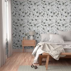 a bed with white sheets and pillows in a bedroom next to a wallpapered wall