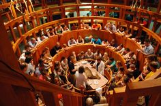 a group of people sitting around a wooden table in a room filled with wood paneled walls