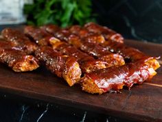 several pieces of meat sitting on top of a wooden cutting board