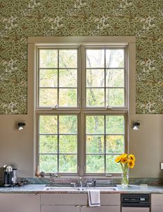 a kitchen with two windows and a sink in front of the window is decorated with yellow flowers