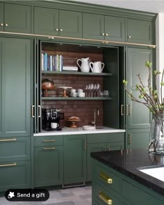 a kitchen with green cupboards and black counter tops, gold trim on the doors