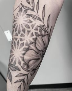 a black and white photo of a woman's leg with a flower tattoo on it