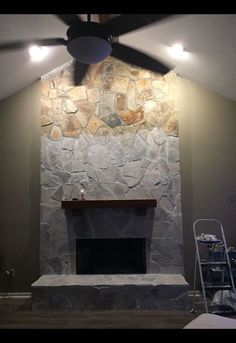 a living room with a stone fireplace and ceiling fan