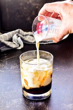 someone pouring something into a glass on top of a table