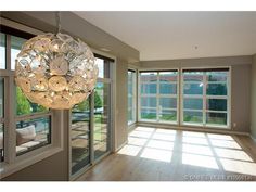 an empty living room with large windows and a chandelier hanging from the ceiling