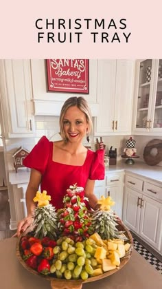 a woman in a red dress holding a platter of fruit with the words christmas fruit tray