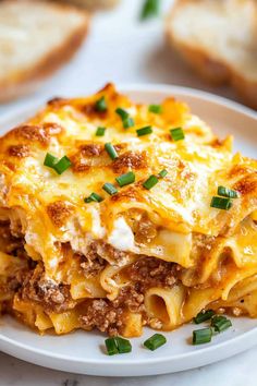 a white plate topped with lasagna covered in meat and cheese on top of bread