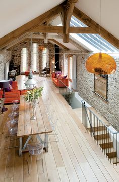 an open floor plan with wood floors and exposed ceilings, stone walls, and vaulted ceiling