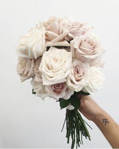 a hand holding a bouquet of white roses