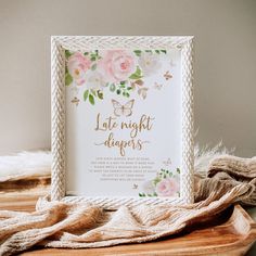 a white frame sitting on top of a wooden table next to a blanket and flowers