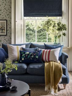 a living room with blue couches and pillows on top of the couch, next to a window