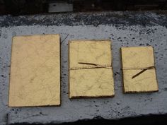 three square pieces of gold colored paper tied to each other with string on top of them