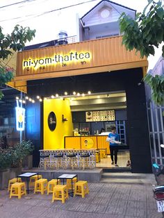 an outdoor restaurant with yellow tables and chairs in front of the building that says niyom - thaftea