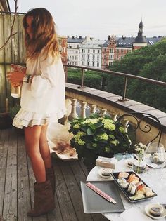 a woman standing on top of a wooden deck next to a table filled with food