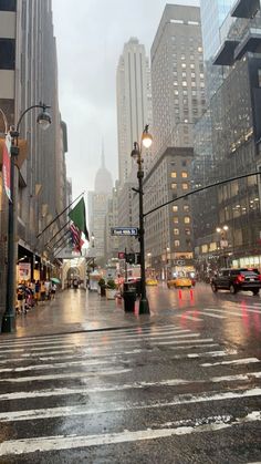 a city street with cars and people on it in the rain