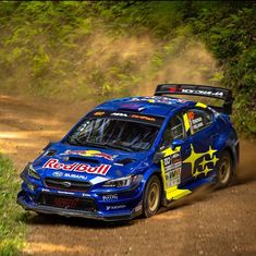 a subaru racing car driving down a dirt road