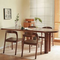 a dining room table with four chairs and a plant in the corner next to it