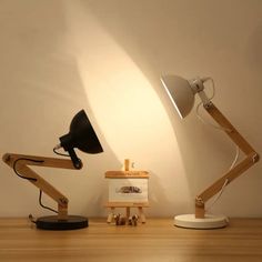 two desk lamps sitting on top of a wooden table