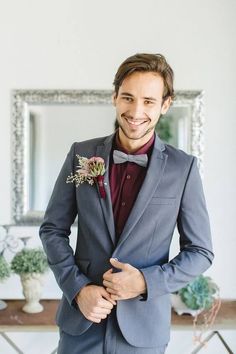 a man in a suit and bow tie standing next to a mirror with his hands on his hips