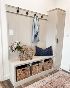 a bench with baskets, coat rack and jacket hanger on the wall next to it