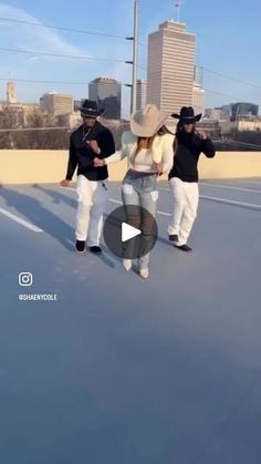 two men in black and white outfits are dancing on a roof with buildings in the background