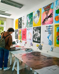 a person standing in front of a table with posters on it