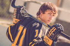 a young man is holding his hockey equipment