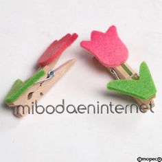 two wooden pegs with pink flowers and green leaves sticking out of them on a white surface