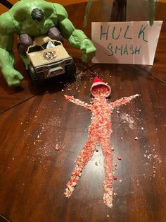 a child's drawing made out of candy sits on a table next to a toy car and hulk smash