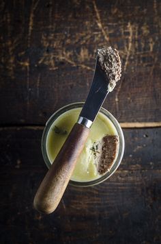 a glass filled with green liquid and a wooden spoon