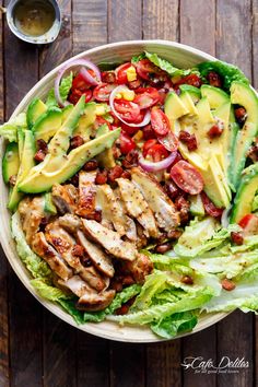 a salad with chicken, lettuce, tomatoes and avocado on top