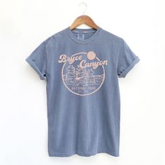 Looking for a cute versatile top to wear this summer? Make sure to grab one of our Vintage Bryce Canyon National Park garment dyed graphic tees! This soft and comfortable graphic tee is the perfect top for any outfit. It can be paired with biker shorts, jeans, or even a simple skirt/dress! This tee is true-to-size, so be sure to order your regular t-shirt size! If you are looking for a more oversized look, make sure to size up! National Park T Shirt Design, Cute T Shirts Graphic Tees Retro Vintage, City Shirt Design, Faded Pre-washed T-shirt For Summer, Summer Soft-washed Washed Blue T-shirt, Travel T Shirt, Vintage Camp Shirt, Simple Tshirt Design Ideas, Event Tshirt Design