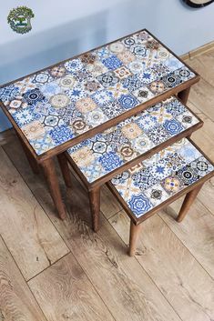 two tables with blue and white tiles on them sitting on the floor next to a clock