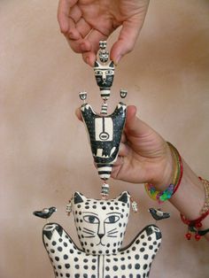 two hands are holding an animal figurine with black and white designs on it