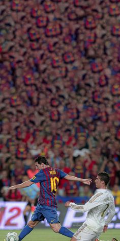 two men playing soccer in front of a large crowd