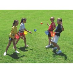 three children playing with toys in the grass on a sunny day, one boy is throwing a ball to the other girl